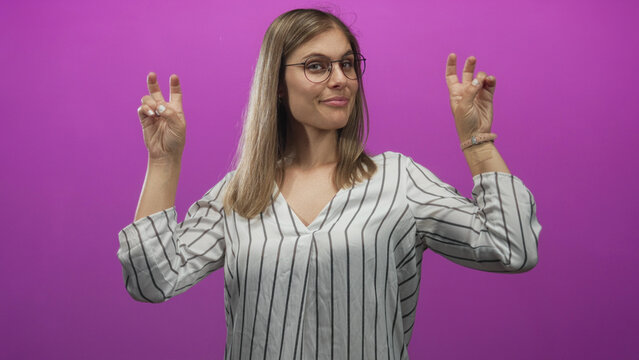 Blonde woman showing air quotes gesture with both hands in a studio with bright magenta background; sarcasm.