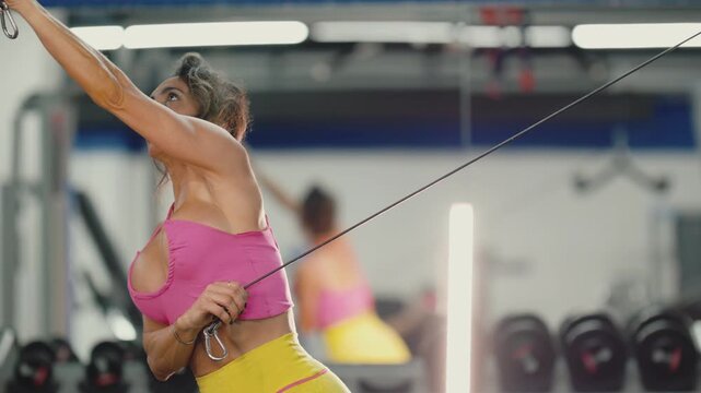 Determined woman performing cable crossover exercise in a gym