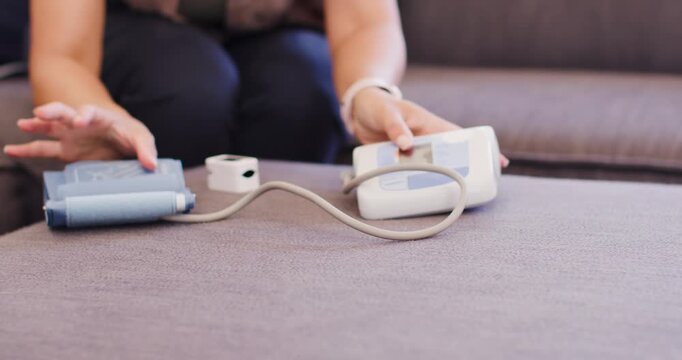 Adult African woman arranging blue cuff white monitor sensor on sofa preparing blood pressure check