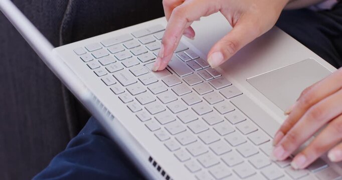 African American woman positioning fingers then typing and using trackpad on silver laptop on lap