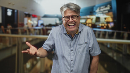 Fototapeta premium Man smiling with hand extended by airport railing, wearing glasses and short sleeve shirt, laughing openly; joy warmth.
