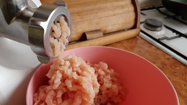 Top view of electric meat grinder mincing chicken meat