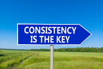 Obraz premium Consistency is the key symbol. Concept words Consistency is the key on beautiful blue road sign. Beautiful blue sky green field background. Business consistency is the key concept. Copy space.