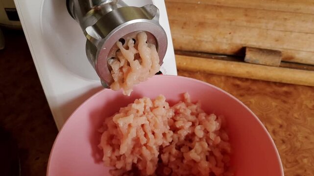 Side view of mincing raw chicken meat in domestic kitchen