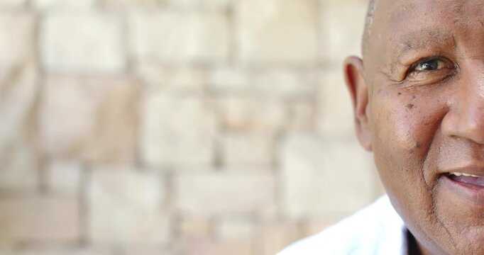 Mature man reacting to offscreen cue smiling squinting by stone wall with white collar, copy space