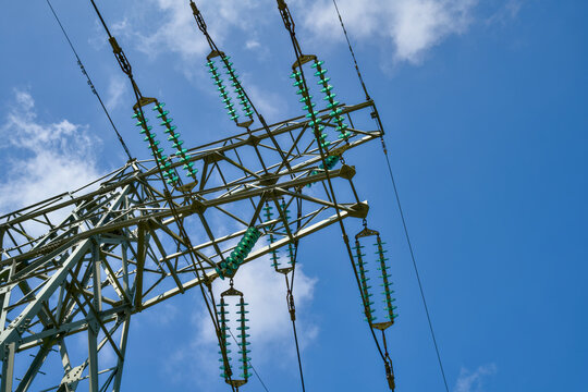 High-voltage transmission tower with power lines against a blue cloudy sky, Dutch electricity grid infrastructure for energy transition. Electriciteitsmast.