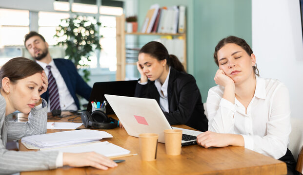 Fatigued young man and women feeling burnout while resting near laptops in office environment