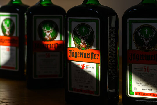 Novi Sad, Serbia - April 4, 2026: Close-up of J&auml;germeister bottles with dramatic shadow lighting on wooden bar surface, revealing the part of the label.