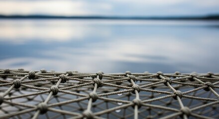 Naklejka premium Close Up Of A Textured Knotted Rope Fence Overlooking A Vast Calm Blue Lake Water Horizon Outdoors