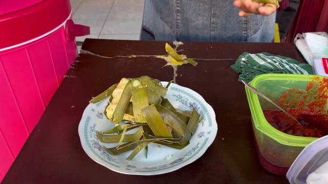 Traditional breakfast cuisine of West Sumatera street food, Ketupat Padang, sticky rice cake packed inside the coconut leaves