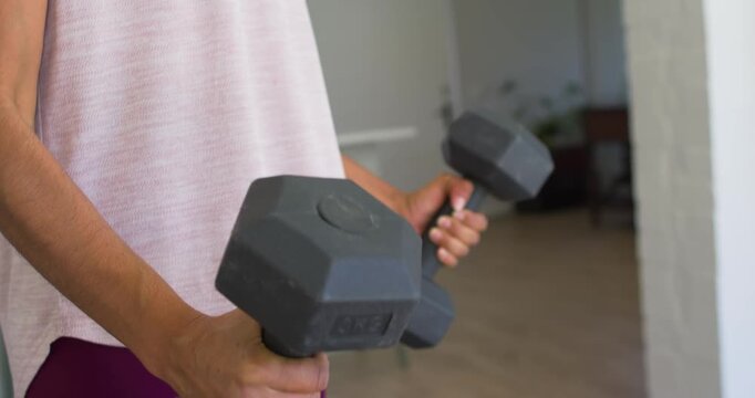 Woman shifting grip and curling 3KG hex dumbbells in home fitness session, camera rising