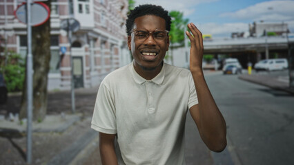 Fototapeta premium Young african american man wearing glasses raises hand to head on busy city street amid cars; confusion.