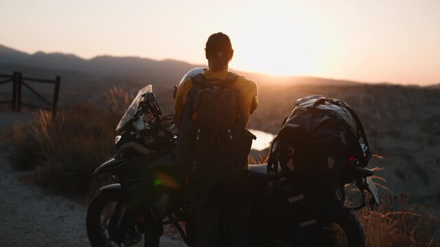 Adventurous motorcyclist kissing helmet before a solo trip at sunset