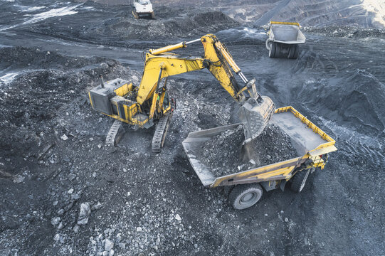 Aerial view of a yellow excavator loading ore into a large dump truck in an open-pit mine Santa Lucia de Gordon, Castile and Leon, Spain.