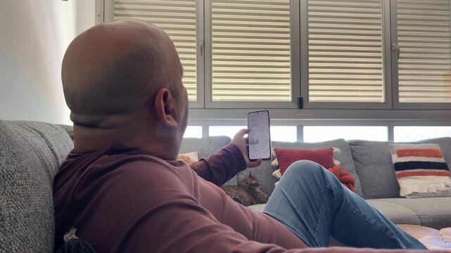 Hombre abriendo persiana con smartphone en casa inteligente