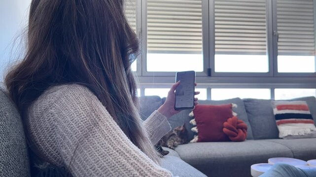 Mujer abriendo persiana con smartphone