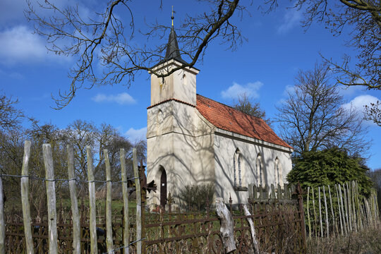 Jager Church Chapel, a small Protestant village chapel built in 1830 surrounded by a rusty iron fence and sections of wooden picket fencing, near Greifswald, Germany