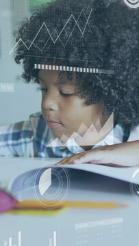Vertical video: Boy leaning into book, reading and writing, HUD charts hovering over book in class
