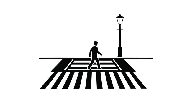 Silhouette of a person walking across a crosswalk beneath a streetlamp
