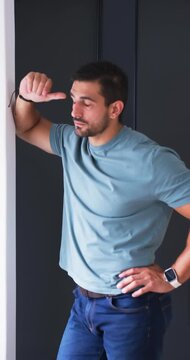 Vertical video: Adult man pausing, leaning on doorjamb in hall, gesturing then rubbing nose to rest