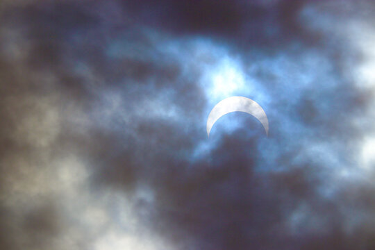 Partial solar eclipse viewed through dramatic clouds in Boise, Idaho.