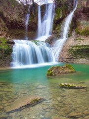Obraz premium Long-exposure shot of the stunning multiple waterfalls and turquoise pool at the Peña Ladros Natural Monument, showcasing the power and beauty of flowing water.