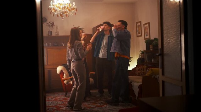 Cheerful Group Of People Toasting Beverages Amid Lively Music And Joyful Dancing In Cozy Kitchen