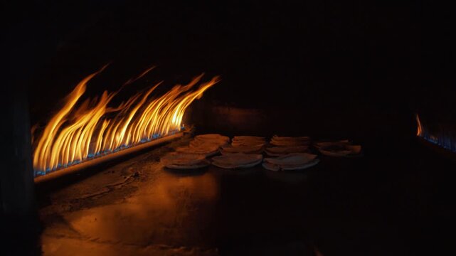 Thin Arabic bread shrak or pita, with lamb meat being cooked inside traditional oven, gas flames over metal plate