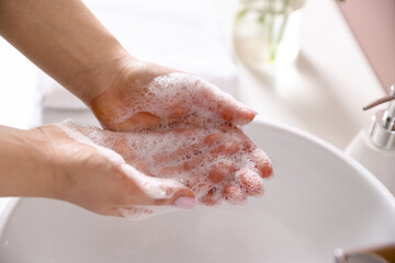 Fototapeta premium Woman washing hands with soap near white sink indoors, closeup