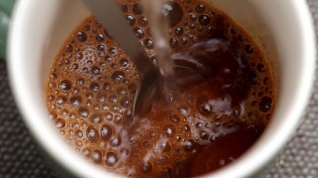 Hot water pouring into a cup with instant chicory powder. Dissolving process creating bubbles and steam. Concept of natural coffee substitute