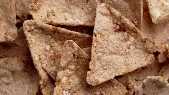 Crispy organic buckwheat nachos with amaranth and quinoa. Triangular tortilla chips with crunchy texture. Gluten-free snack. Top view. Rotation