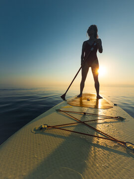 Young woman walking on sup board by the sea during summer vacation