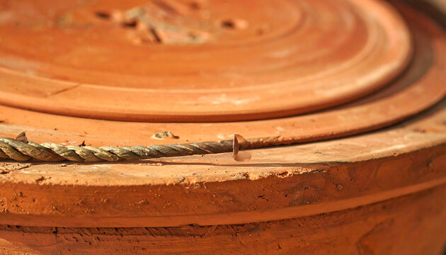 Close up of weathered terracotta pot detail with rope and nail