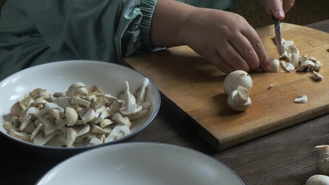 Cutting fresh champignons with a knife on a cutting board