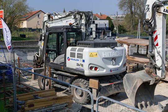 Mirecourt, France - March 21st 2026 : View of a 14-tonne grey compact wheeled excavator Hitachi ZX140W-6 on a construction site for work on the district heating network.