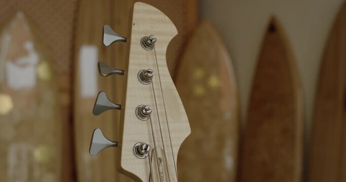 Close up of headstock and tuning pegs on four string electric bass guitar with flamed maple wood grain