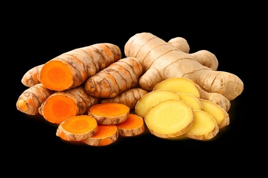 Fresh turmeric and ginger root slices on a black background