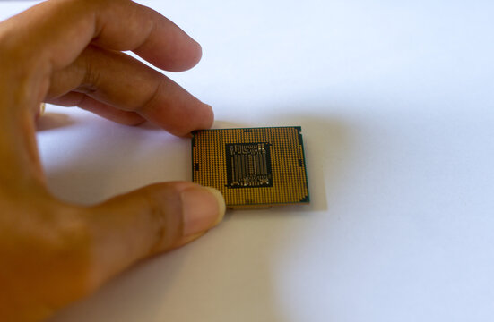Close-up of a person holding a gold-plated computer CPU microchip in their palm. Concept of technology, computing power, hardware, and digital innovation.