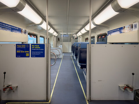 LOS ANGELES, CA, FEB 9, 2026: Empty Metrolink commuter train car interior with bike storage area, blue seats, fluorescent lighting, safety signage, and a wide central aisle