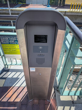 LOS ANGELES, CA, FEB 13, 2026: newly installed LA Metro station tap-to-pay validator kiosk, with contactless reader, small screen, and a suicide crisis line poster nearby