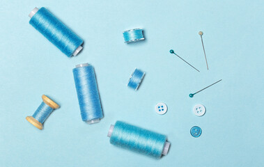 Fototapeta premium Sewing kit, blue threads on spools and sewing bobbins, buttons, top view.