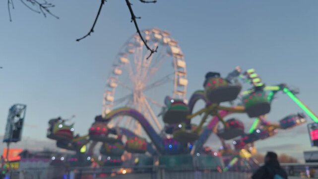 Romantic fairground illuminated under twilight sky. Serene theme park with luminous attractions and quiet visitors. Calm amusement park scene featuring bright rides and peaceful guests during sunset