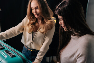 Fototapeta premium Two female friends checking suitcase, preparing for exciting journey, packing baggage for upcoming adventure and vacation planning. Concept of organization and travel essentials.