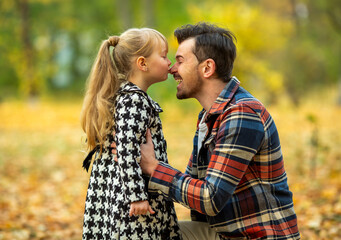 Fototapeta premium Father and daughter touching noses in autumn park.