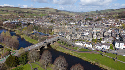 A sweeping panoramic view of Peebles, a prominent market town in the Scottish Borders. This perspective highlights the town's extensive layout along the river valley, surrounded by the rolling green h © MAKSYM