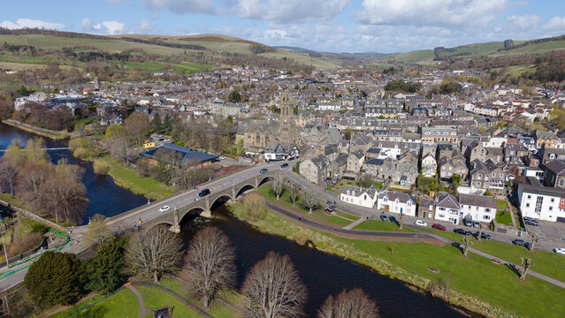 A sweeping panoramic view of Peebles, a prominent market town in the Scottish Borders. This perspective highlights the town's extensive layout along the river valley, surrounded by the rolling green h