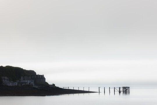 An old pier at Hawcraig Point in a minimalist seascape scene on the Firth of Forth in the fog, Aberdour, Fife, UK.