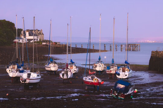 Scenic, picturesque view of Aberdour Harbour at low tide during a colourful summer evening sunset.