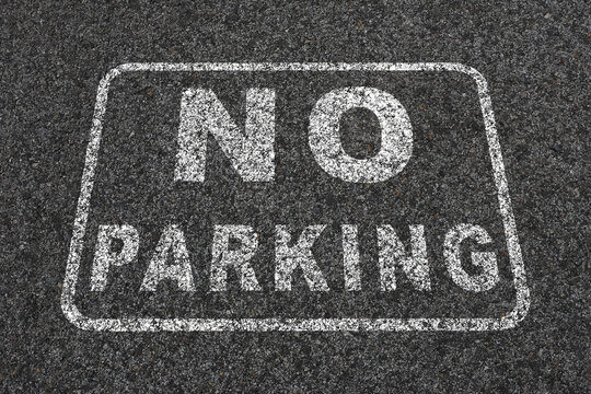 design on a dark asphalt. The text reads 'NO PARKING' in bold, capital letters