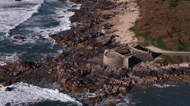 Aerial view of Forte do Cao where foamy waves crash against the rugged coastline, contrasting with the fort's stoic stone, Vila Praia de Ancora, Portugal.